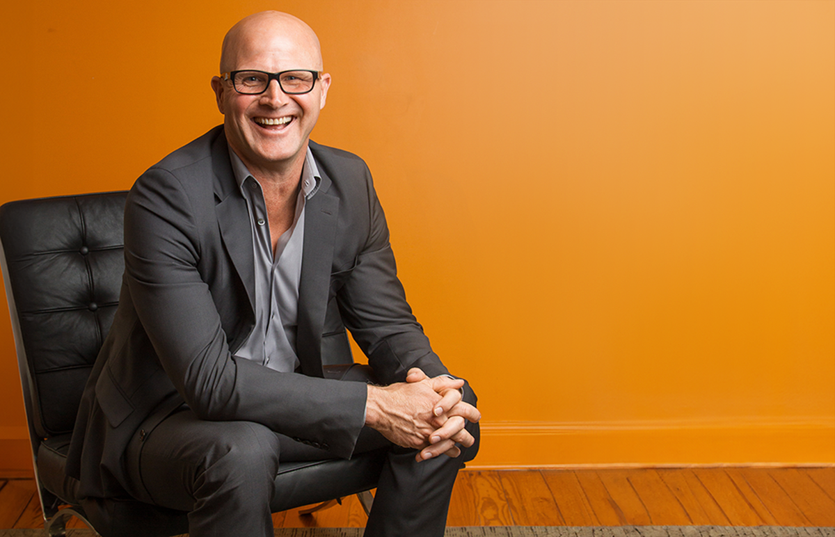 Executive in black chair against Orange wall